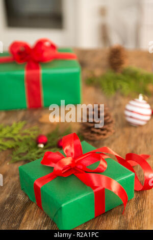 DIY Geschenkverpackung. Wunderschöne grüne Weihnachten Geschenke mit roter Schleife auf rustikalen Holztisch. Weihnachtsgeschenke verpacken. Stockfoto