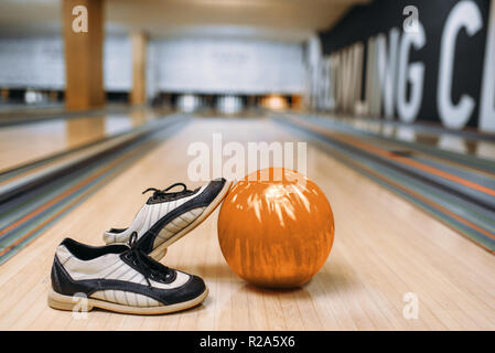 Bowling Ball und Schuhe auf dem Holzboden in Club, Stifte auf Hintergrund, niemand. Schüssel Spiel Konzept, tenpin Stockfoto