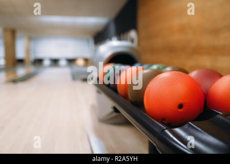 Farbe bowling Bälle in der Zuführung, Fahrspurassistent mit Pins auf Hintergrund, niemand. Schüssel Spiel Konzept Stockfoto