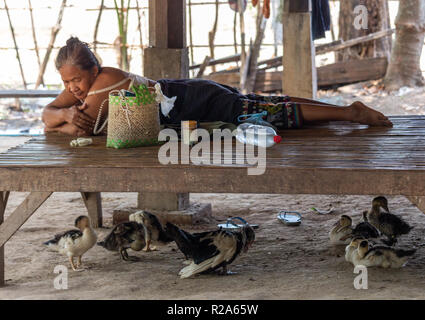 Don Det, Laos - April 24, 2018: Lokale Frau chillen im Schatten von ihrem Garten umgeben von Enten Stockfoto