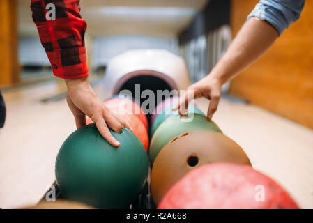 Zwei männliche Bowlers bringt Bälle vom Schrägförderer. Kegelbahn Spieler bereitet sich auf einen werfen. Klassische tenpin Spiel im Club, aktive Freizeit Stockfoto