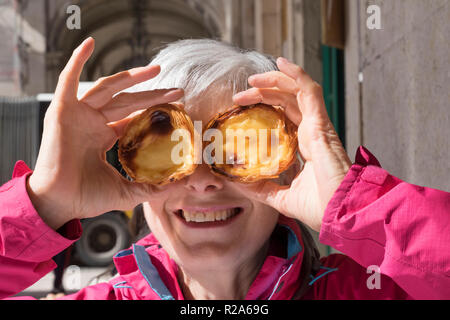 Pasteis de Nata, Senior Frau mit traditionellen Lissabon Pudding zu ihrem Gesicht Stockfoto