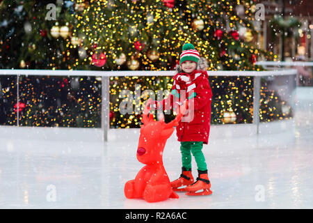 Kinder Eislaufen im Winter Park Rink. Kinder Eislaufen am Weihnachtsmarkt. Kleine Junge mit Schlittschuhen auf kalter Tag. Schnee Spaß im Freien für Kind. Winter spo Stockfoto