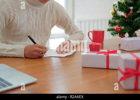 Mann mit Creme Pullover schreiben Weihnachten schreiben Grußkarte Urlaub wünsche mit Weihnachten Dekoration. Stockfoto