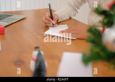 Mann mit Creme Pullover schreiben Weihnachten schreiben Grußkarte Urlaub wünsche mit Weihnachten Dekoration. Stockfoto