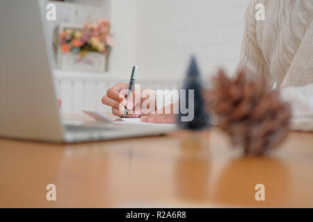 Mann mit Creme Pullover schreiben Weihnachten schreiben Grußkarte Urlaub wünsche mit Weihnachten Dekoration. Stockfoto