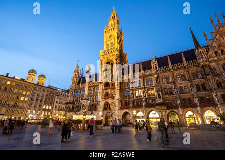 Neues Rathaus (mit Uhrturm und Glockenspiel) und Masse (gewölbte Türme der Frauenkirche links), Marienplatz, München, Deutschland Stockfoto