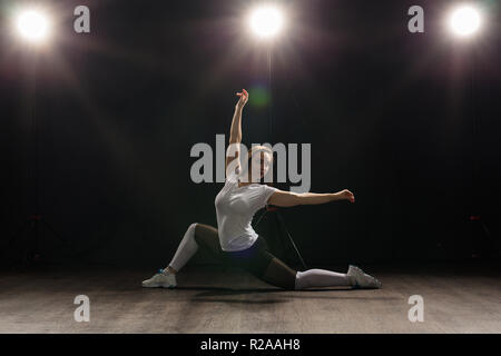 Dance, Hip Hop, Jazz Funk und Personen Konzept - flexible junge Frau tanzen in der Dunkelheit unter dem Licht Stockfoto