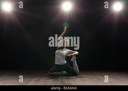 Dance, Hip Hop, Jazz Funk und Personen Konzept - flexible junge Frau tanzen in der Dunkelheit unter dem Licht Stockfoto