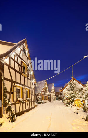 Ein altes Dorf Straße mit Fachwerkhäusern und Weihnachten Dekoration in der Nacht bei Schneefall in Haines, Edenkoben, Deutschland. Stockfoto