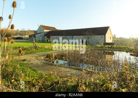Folly Farm in der Nähe von Bristol, Ansicht von einer der Unterkünfte Blöcke auf Teich Stockfoto