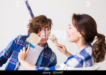 Familie, Renovierung, Glück und Renovierung Konzept - junge Familie tun, Reparatur, Anstrich Wände zusammen und lachen Stockfoto