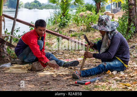 Don Det, Laos - April 24, 2018: Lokale Männer manuelle arbeitet mit Bambus in der Nähe des Mekong River Stockfoto