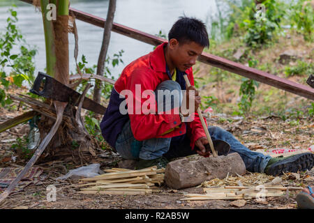 Don Det, Laos - April 24, 2018: Lokale Mann manuelle arbeitet mit Bambus in der Nähe des Mekong River Stockfoto