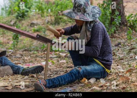 Don Det, Laos - April 24, 2018: Lokale Mann manuelle arbeitet mit Bambus in der Nähe des Mekong River Stockfoto