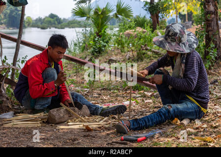 Don Det, Laos - April 24, 2018: Lokale Männer manuelle arbeitet mit Bambus in der Nähe des Mekong River Stockfoto