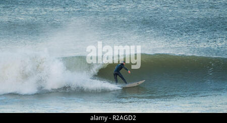 Aberystwyth Wales, UK. 18 Nov, 2018. UK Wetter: Hardy Surfer früh auf die beeindruckenden Wellen in der Morgensonne in Aberystwyth auf der Cardigan Bay Küste von West Wales zu fangen. Foto credite Kredit: Keith Morris/Alamy leben Nachrichten Stockfoto