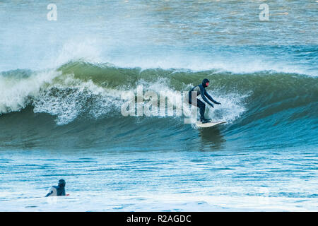 Aberystwyth Wales, UK. 18 Nov, 2018. UK Wetter: Hardy Surfer früh auf die beeindruckenden Wellen in der Morgensonne in Aberystwyth auf der Cardigan Bay Küste von West Wales zu fangen. Foto credite Kredit: Keith Morris/Alamy leben Nachrichten Stockfoto