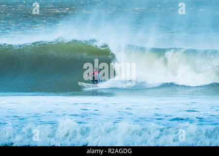 Aberystwyth Wales, UK. 18 Nov, 2018. UK Wetter: Hardy Surfer früh auf die beeindruckenden Wellen in der Morgensonne in Aberystwyth auf der Cardigan Bay Küste von West Wales zu fangen. Foto credite Kredit: Keith Morris/Alamy leben Nachrichten Stockfoto