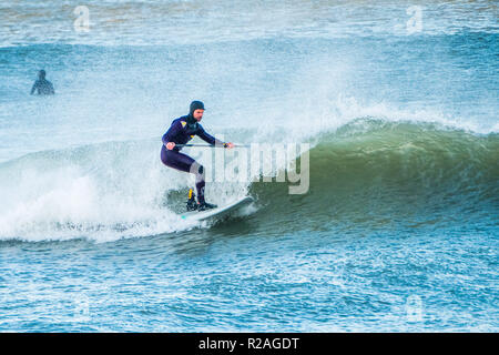 Aberystwyth Wales, UK. 18 Nov, 2018. UK Wetter: Hardy Surfer früh auf die beeindruckenden Wellen in der Morgensonne in Aberystwyth auf der Cardigan Bay Küste von West Wales zu fangen. Foto credite Kredit: Keith Morris/Alamy leben Nachrichten Stockfoto