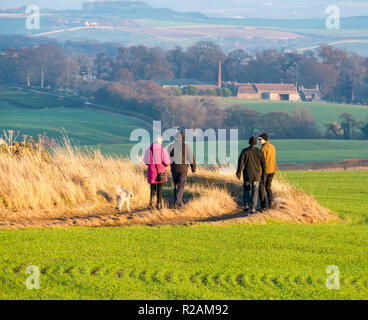 East Lothian, Schottland, Vereinigtes Königreich, 18. November 2018. UK Wetter: ein klarer Himmel und Sonnenschein an einem Herbsttag. Eine Gruppe von Wanderern und ein Hund genießen Sie den Blick über die Hügel eine landwirtschaftliche Landschaft Stockfoto