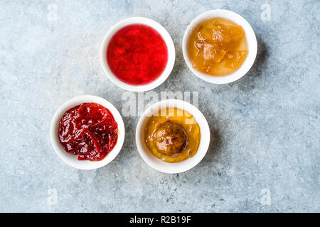 Sortierte Auswahl an Konfitüren und Marmeladen; Rose, rot Pfeffer, Mandarine und Zitrone schälen in kleine Schüssel. Ökologische Lebensmittel. Stockfoto