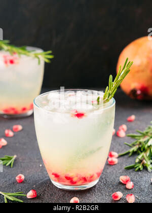 Herbst und Winter cocktails Idee - weiße Sangria mit Rosmarin, pomegrante und Zitronensaft und Zutaten auf schwarzem Zement Hintergrund. Stockfoto