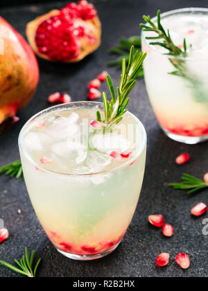 Herbst und Winter cocktails Idee - weiße Sangria mit Rosmarin, pomegrante und Zitronensaft und Zutaten auf schwarzem Zement Hintergrund. Stockfoto