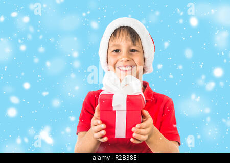 Kind Junge in Weihnachten Santa Hat und Red vorhanden Box auf Weiß. Stockfoto
