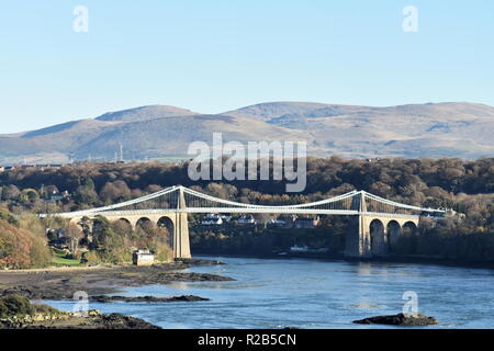 Blick auf die Menai Brücke von der schönen walisischen Insel Anglesey. In der Ferne die Berge von Snowdonia. Blauer Himmel mit Kopierraum. Stockfoto