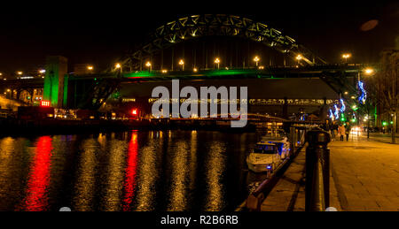 Fluss Tyne in der Nacht mit Beleuchtung auf Swing Bridge, High Level Bridge und Tyne Bridge und Menschen zu Fuß auf Riverside, Newcastle, England, Großbritannien Stockfoto