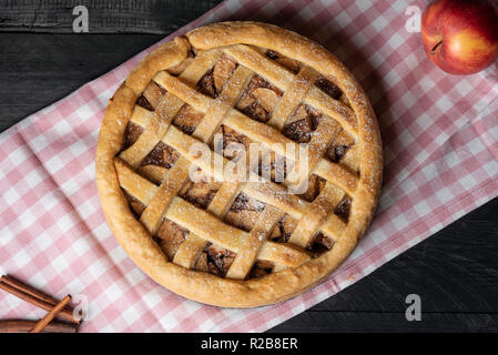 Oben Ansicht einer köstlichen hausgemachten Apfelkuchen mit Gitter Kruste, auf einer rosa Handtuch, auf einem Holztisch. Frisch gebackene Desserts. Nationale pie Tag. Stockfoto