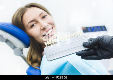 Zahnmedizinische Klinik. Rezeption, die Untersuchung des Patienten. Zähne kümmern. Zahnarzt mit Zahn Farbmuster auswählen Schatten für Frauen Patienten Zähne in der Zahnarztpraxis Stockfoto