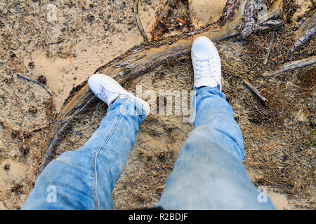 Beine in weißen Turnschuhen und Jeans unter Natur Stockfoto