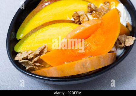 Kürbisscheiben Backen im Ofen, Mango. Haferflocken, Schlagsahne, getrocknete Früchte auf einem Teller mit Kürbis und Mango Stockfoto