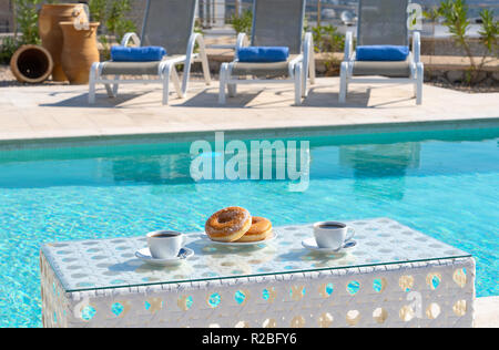 Donuts und Kaffee, die nicht für das Frühstück am Pool Stockfoto