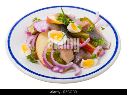 Norwegische Küche, Heringssalat mit Apfel und eingelegte Gurken garniert mit Frühlingszwiebeln und Wachteleier. Auf weissem Hintergrund Stockfoto