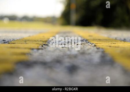 Raum zwischen gelb Trennlinien auf einer Straße in Texas; niedrige Perspektive und verschwindende Focal Point. Stockfoto