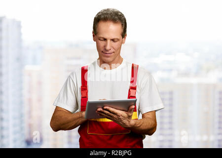 Arbeiter mit digitalen Tablet. Im mittleren Alter builder Arbeiten am Computer Tablet. Leute, Bau, Technologie. Stockfoto