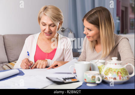 Pflege home Rechnungswesen. Tochter und ihren älteren Mutter sind Anschauen von Dokumenten Stockfoto