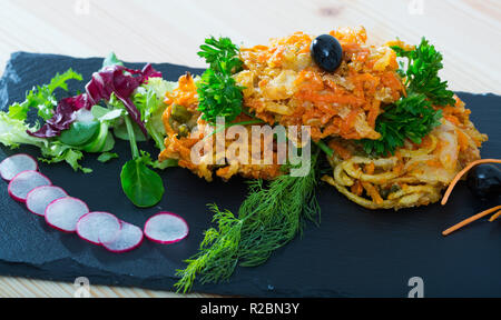 Frittiertes Gemüse in Teig mit gemischter Salat serviert, Scheiben von kleinen Radieschen und schwarzen Oliven Stockfoto