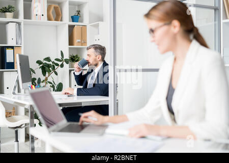 Geschäftsmann Kaffee trinken während der Arbeit im Büro Stockfoto