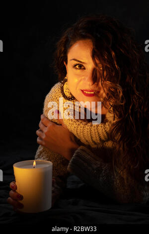 Junge Mädchen, dass eine Kerze mit dem Schein der Lagerfeuer auf ihrem Gesicht. Der Ausdruck spiegelt sich Glück und Hoffnung, sie schaut in die Kamera Stockfoto