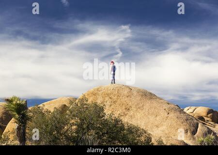 Kind stehend auf Boulder in der malerischen Landschaft der Wüste von Joshua Tree National Park im südlichen Kalifornien USA Suchen Stockfoto