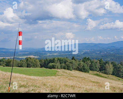 Rot und Weiß Wind Kegel in einer hügeligen Landschaft mit Wald Stockfoto