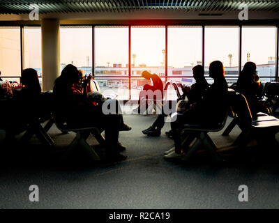 BANGKOK, THAILAND - 1. November 2018: Passagiere sitzen auf Stühlen warten in der Nähe der Fenster Glas warten zum Einsteigen in das Flugzeug auf dem Sunset in Eve Stockfoto