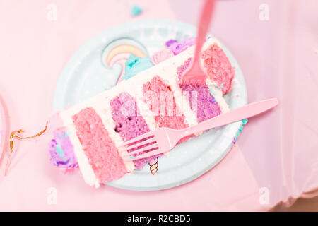 In Scheiben geschnitten groß Einhorn Kuchen mit rosa und lila Kuchen Schichten auf der kleinen Mädchen Geburtstag. Stockfoto