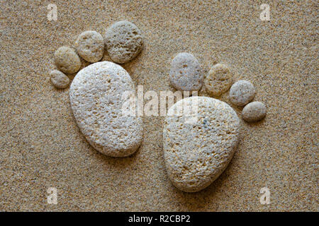 Hinterlassen Sie nur Ihre Abdrücke-funky Spuren sind durch Umstellung ein paar Kieselsteine am Strand erstellt. Stockfoto