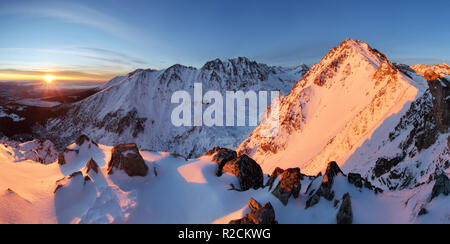 Snowy Mountains unter orange Sonnenuntergang Himmel Stockfoto