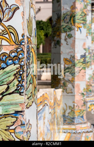 Bunte Fliesen- Säulen und Sitzbank im Garten des Kreuzgangs im Santa Chiara Kloster in der Via Santa Chiara, Neapel, Italien. Stockfoto